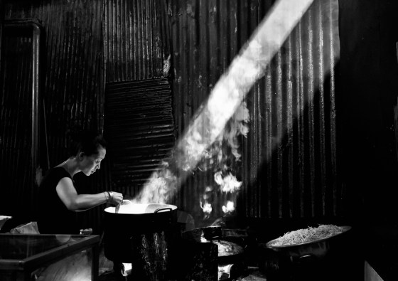 Cambodian woman cooks by natural light.